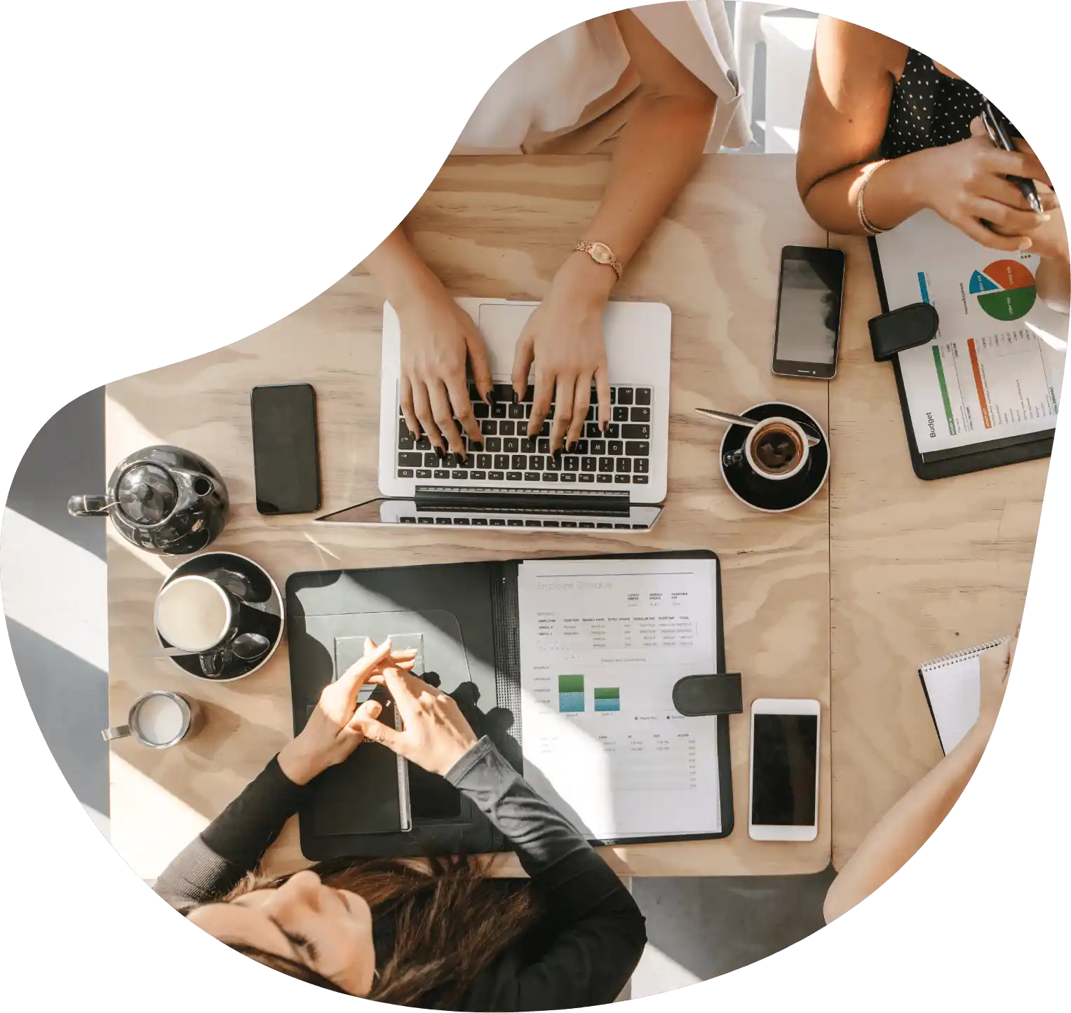 Vue plongeante sur deux personnes en pleine discussion autour d’une table de travail, avec dispositifs numériques et documents bien organisés.