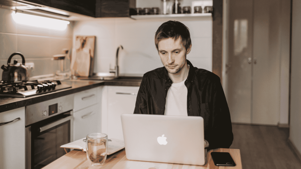 Entrepreneur travaillant sur un ordinateur portable à la maison, avec une tasse sur la table, analysant ses chiffres.