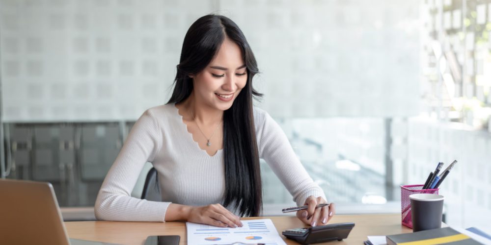 Business women using calculator at working with financial report.