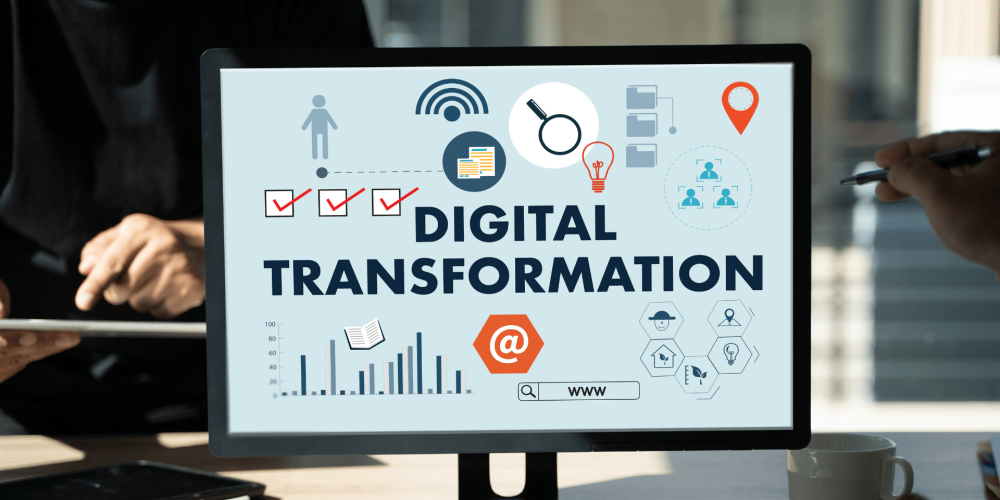 Écran d’ordinateur affichant « Digital Transformation », avec des mains sur un clavier au premier plan.