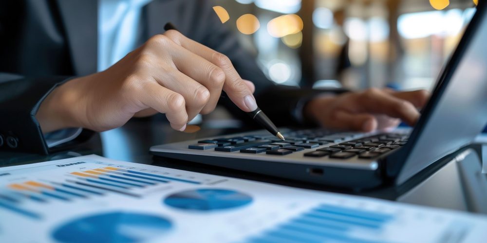 Main utilisant un ordinateur portable avec des graphiques et indicateurs de performance sur l’écran, dans un contexte d’expertise comptable
