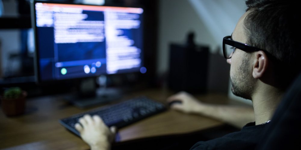 hacker in headset and eyeglasses with keyboard hacking computer system or programming